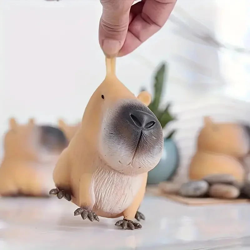 A hand is holding a squishy capybara stress relief toy with realistic fur texture.