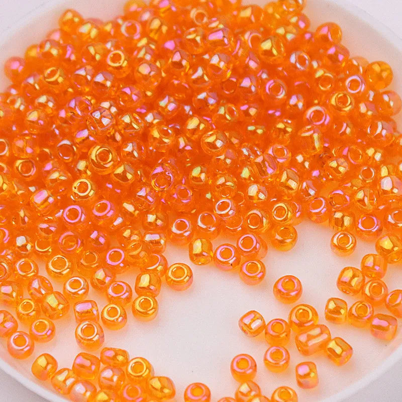 A pile of small, translucent orange glass rice beads for DIY jewelry and crafting.