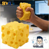A hand squeezes a yellow cheese wedge squishy stress relief toy next to a computer screen.