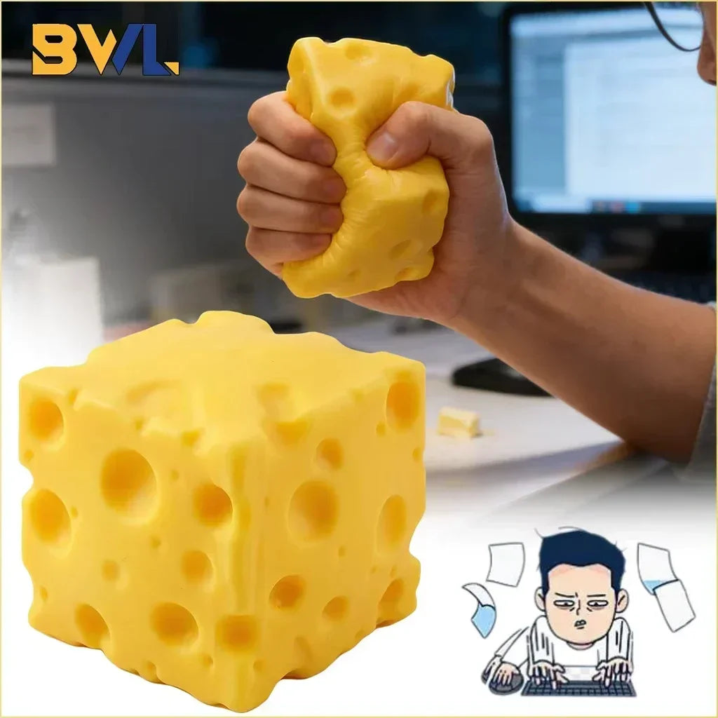 A hand squeezes a yellow cheese wedge squishy stress relief toy next to a computer screen.