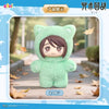 A soft green plush cat character with large eyes is displayed in a light outdoor setting surrounded by fallen autumn leaves.