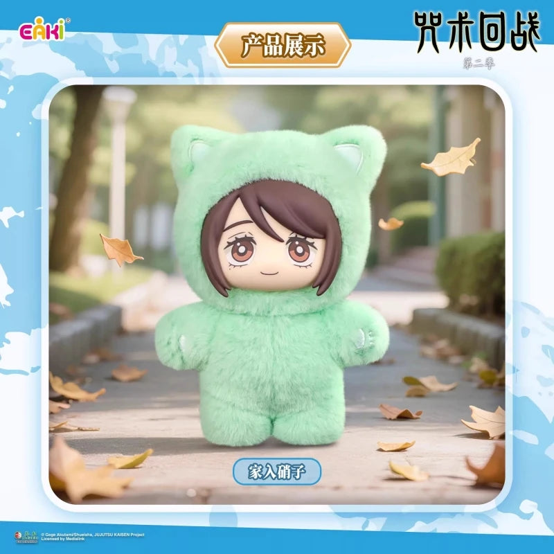 A soft green plush cat character with large eyes is displayed in a light outdoor setting surrounded by fallen autumn leaves.