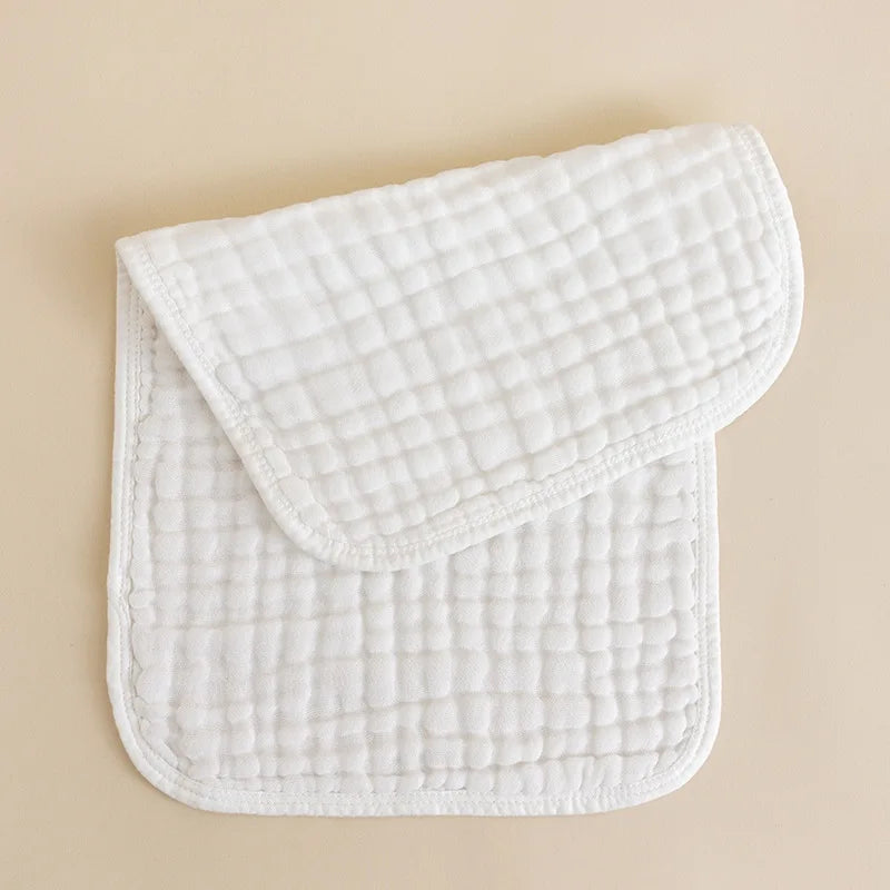 Ein Set aus drei weißen Baby-Puschelchen, gefaltet auf einer hellbeigen Oberfläche.