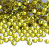 A close-up view of numerous round, faceted yellow glass crystal rhinestones scattered on a white surface.