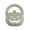 A light green silicone pumpkin baby teether with a textured rim and carved face features for soothing relief.
