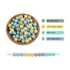A bowl filled with various silicone round beads in shades of gray, yellow, and blue, alongside a line of similar colored bead