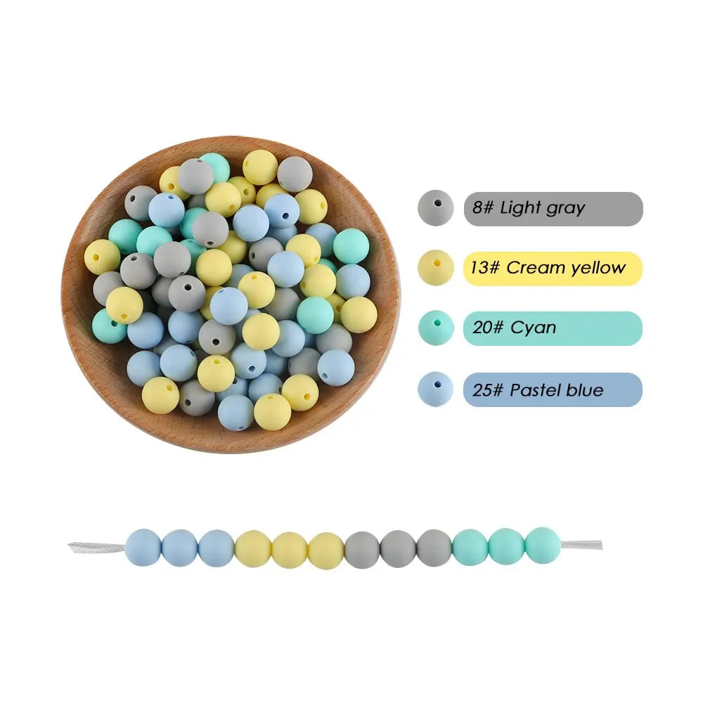 A bowl filled with various silicone round beads in shades of gray, yellow, and blue, alongside a line of similar colored bead