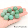 A hand holds several smooth green aventurine crystal spheres.