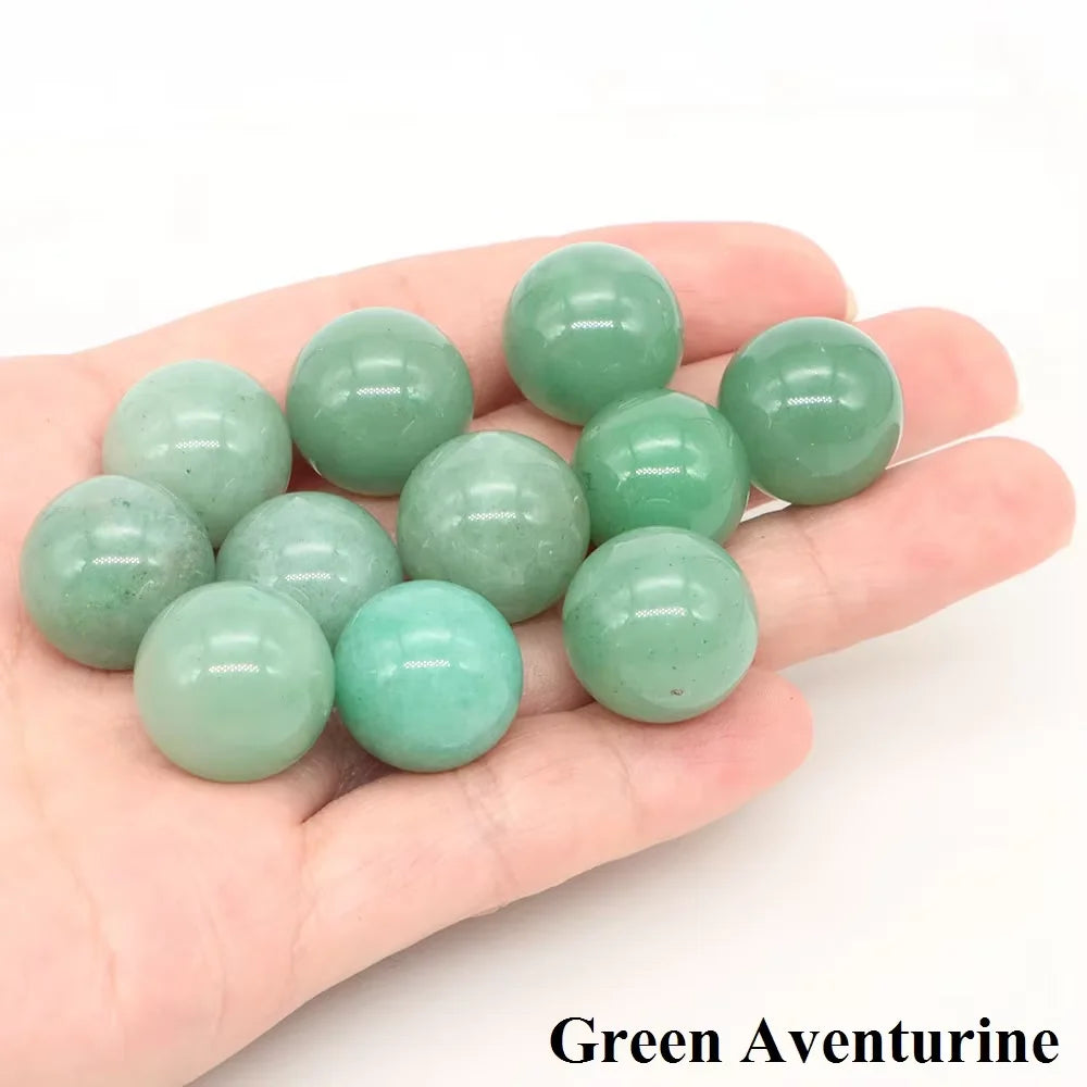 A hand holds several smooth green aventurine crystal spheres.