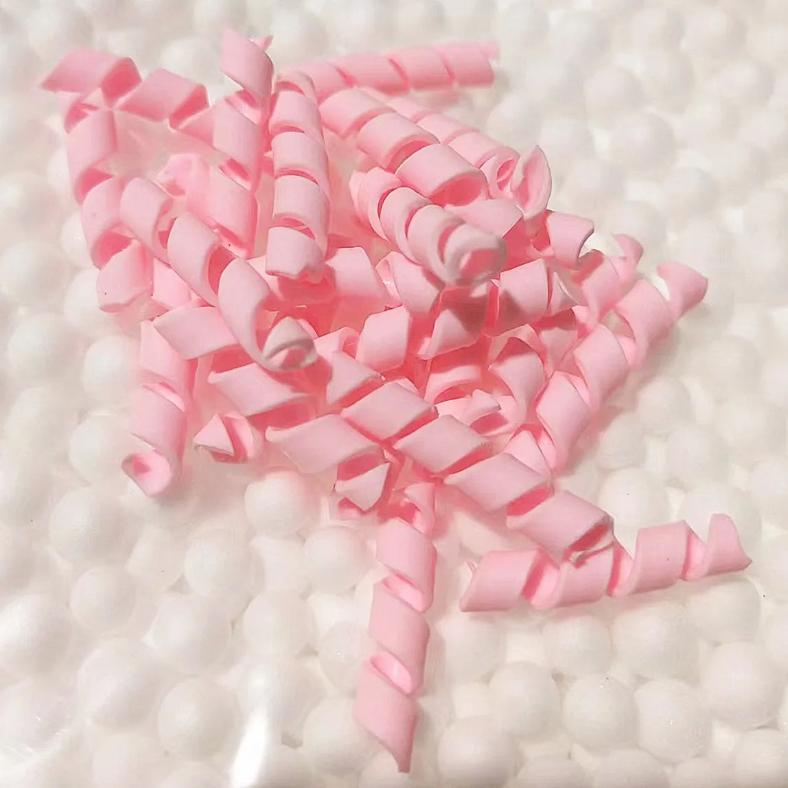 A pile of pink polymer clay marshmallow charms for DIY crafts