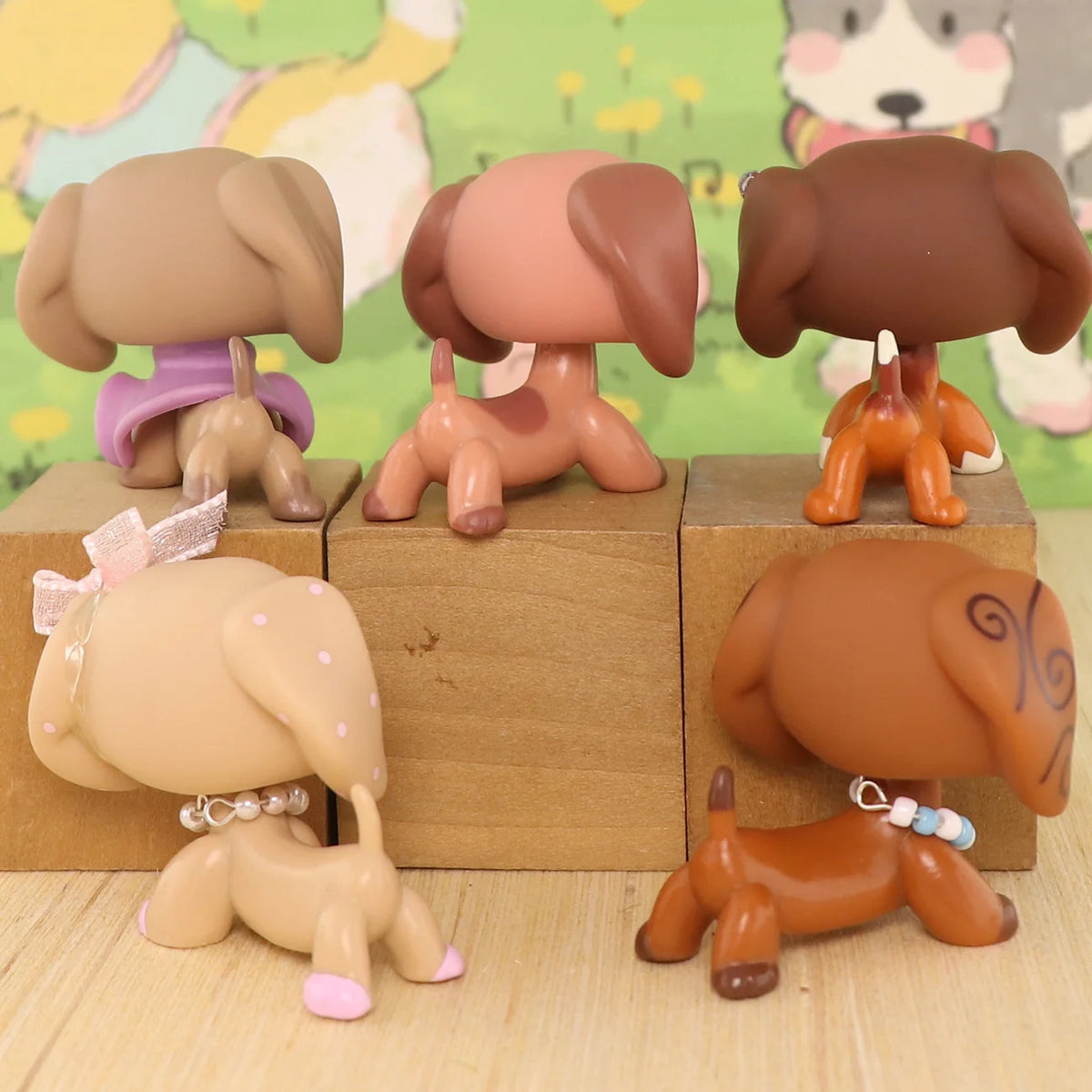 A set of five dachshund bobblehead figurines in various shades of brown and tan, displayed on a wooden surface.