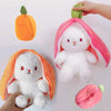 A white plush bunny toy shaped like an orange fruit, with a pink fabric hood and an orange pumpkin accessory.