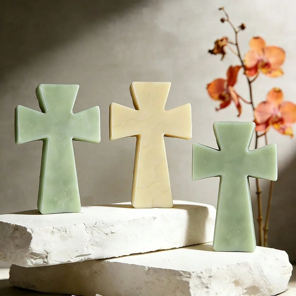 Three pale green and cream silicone cross molds displayed on white stone blocks.