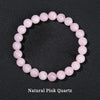 A bracelet made of smooth, round natural pink quartz beads arranged in a circle.