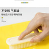 A hand is using a natural-fiber brush on a yellow fabric, demonstrating the durability of the product.