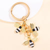 Gold-toned enamel flower keychain featuring a bee design with black and white stripes
