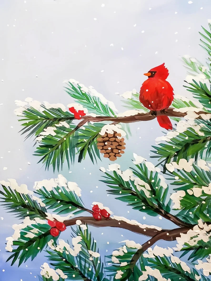 A vibrant red cardinal perched on a branch of pine needles covered in white snow against a pale blue sky.