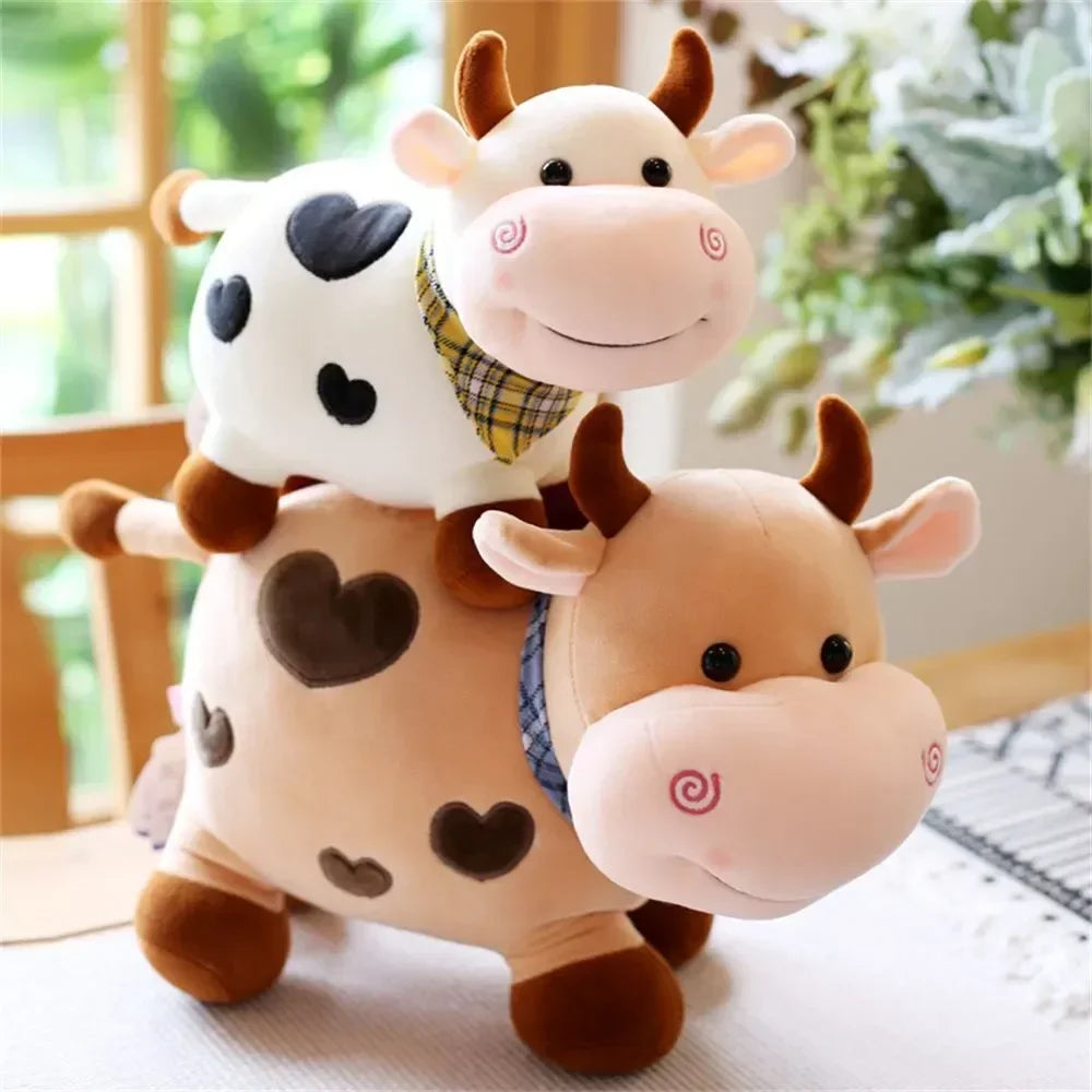 A soft, cuddly plush toy of a white and tan cow with black spots and pink features.
