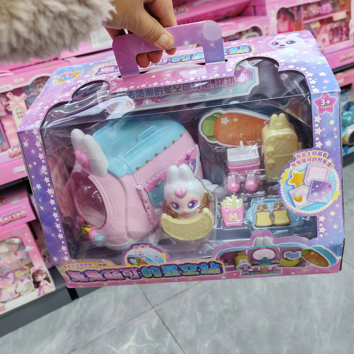 A packaged collectible figure of a doll with pink and white accents inside a clear plastic box.