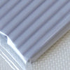 A close-up view of a plastic package containing soft modeling clay, showing its ribbed texture.
