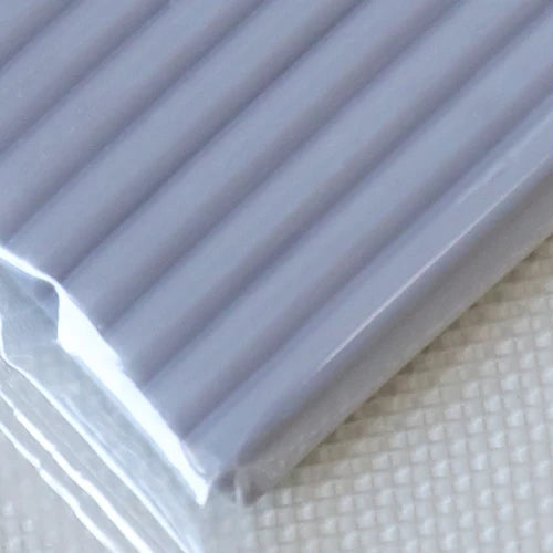 A close-up view of a plastic package containing soft modeling clay, showing its ribbed texture.