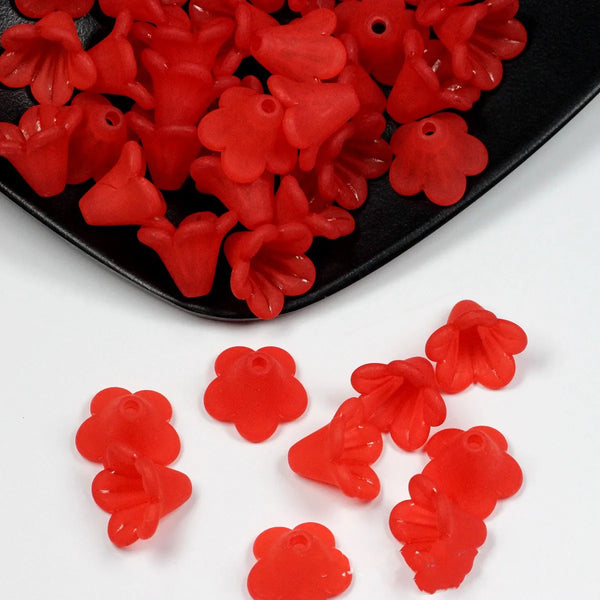 Un montón de cuentas de flores acrílicas esmaltadas de color rojo brillante para hacer joyas.