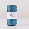 A spool of metallic blue glitter yarn for knitting and crochet with a white label.