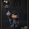 A collectible figure of a dark-haired character wearing a hooded outfit, displayed next to a skull monster figure.