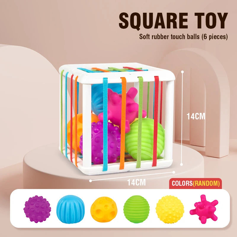 A white container holds six colorful soft rubber touch balls for a toddler shape-sorting toy set.