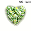 A heart-shaped dish filled with ten green and yellow printed silicone beads for DIY jewelry making