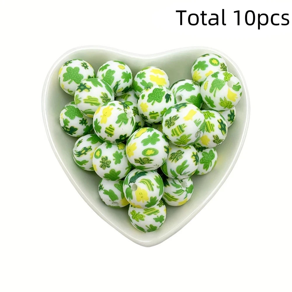 A heart-shaped dish filled with ten green and yellow printed silicone beads for DIY jewelry making