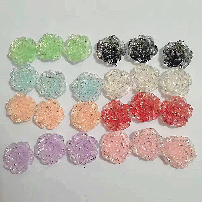 A collection of 50 small, flatback rose-shaped flowers made from resin in various shades of green, gray, white, and pink.