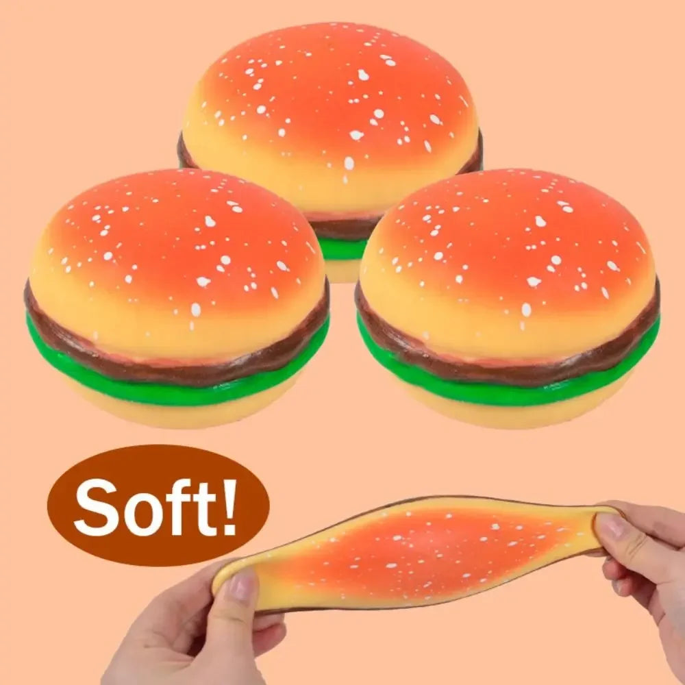 A bright orange and yellow squishy toy shaped like a hamburger bun with sesame seeds, being held by a hand.