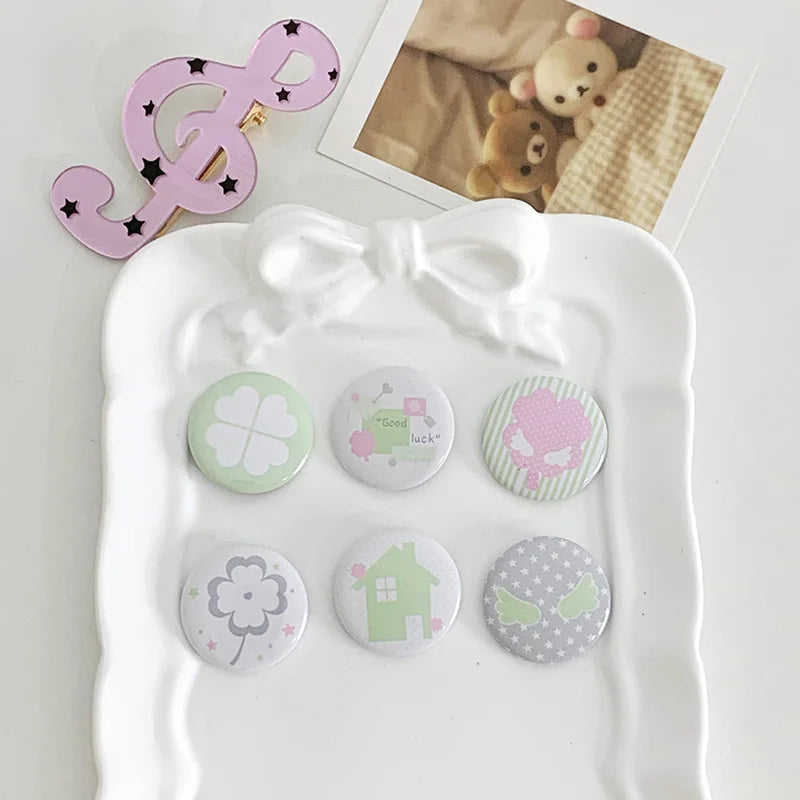 A set of seven kawaii mini pin badges featuring various themes like luck and houses on a white tray.