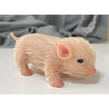 A realistic soft silicone piglet mini doll with pink fur and a black eye, resting on a white surface.