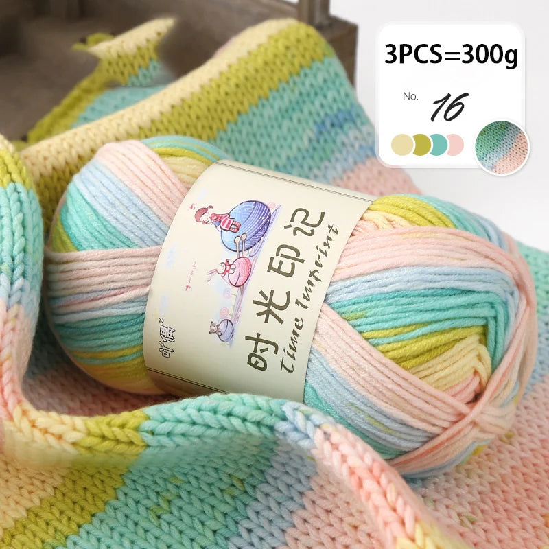 A ball of multi-colored gradient acrylic yarn is shown on a pink background, ready for knitting or crochet.