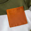 A close-up of an orange fabric patch sewn onto a olive green and white sweatshirt set.
