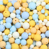 A close-up view of various matte acrylic beads in shades of yellow, blue, and white.
