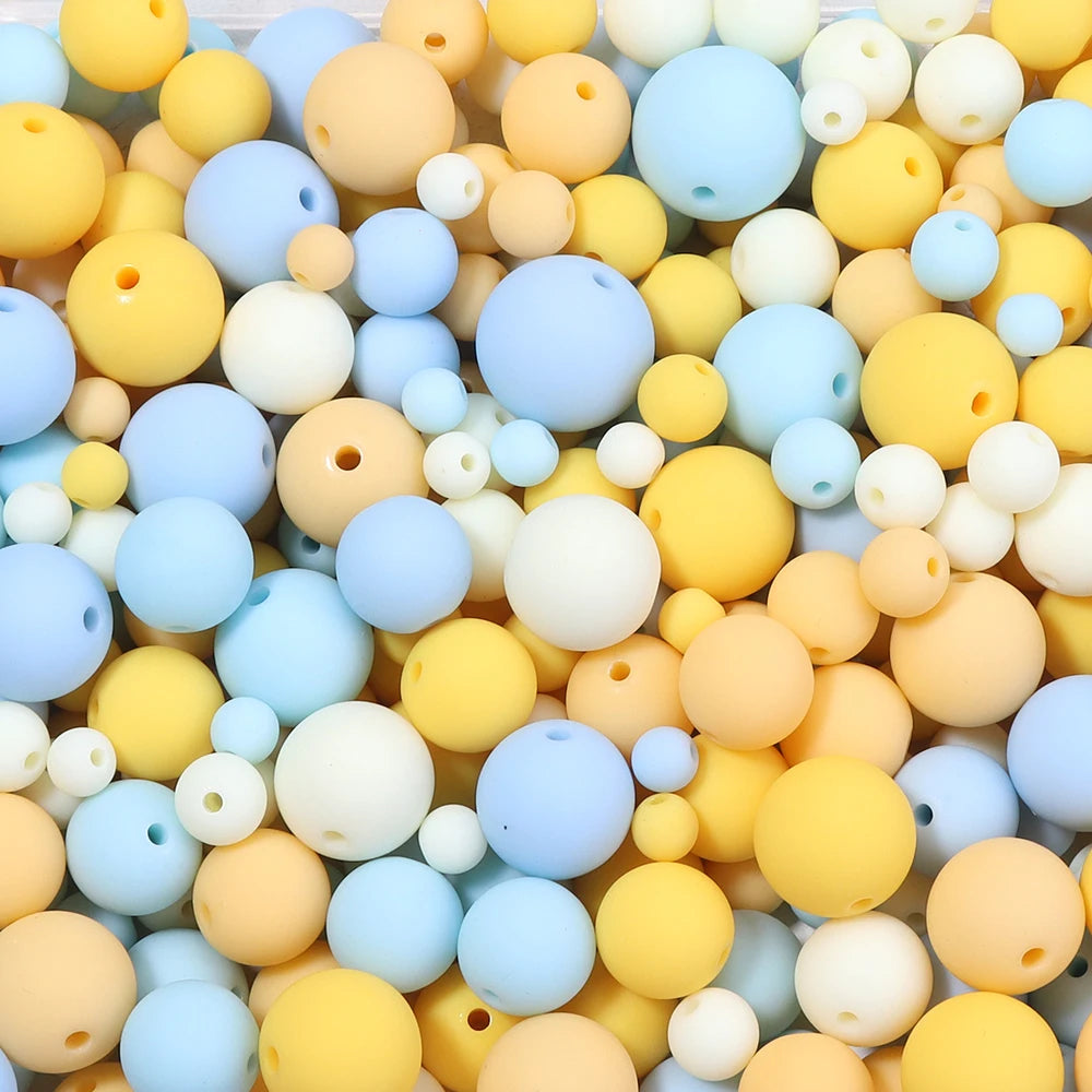 A close-up view of various matte acrylic beads in shades of yellow, blue, and white.