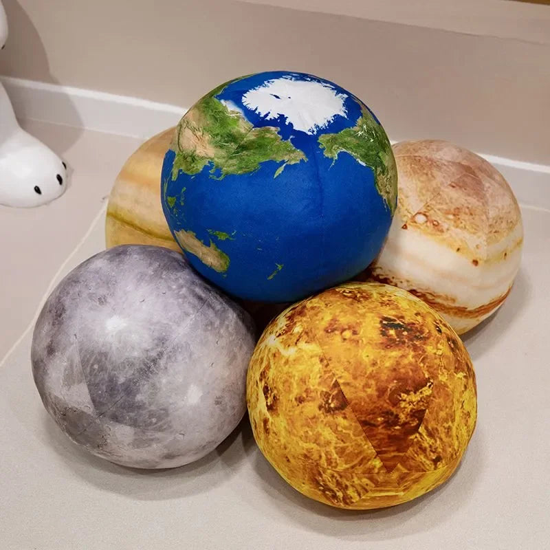 A set of spherical plush toys representing the Earth and the Sun, including a blue globe, a yellow sun, and a gray celestial 