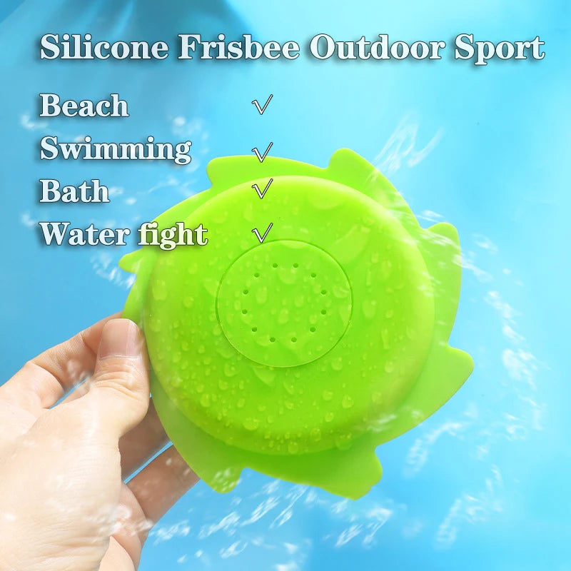 A hand holds a bright green silicone frisbee toy designed for outdoor sports, swimming, and bath play.