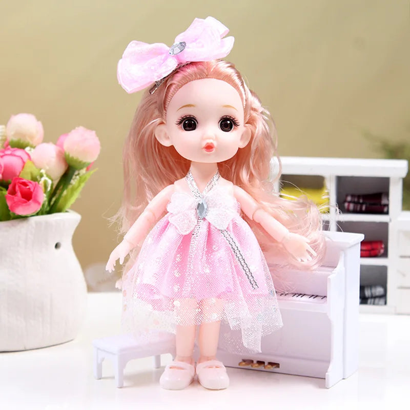 A pink articulated princess doll with a sparkly dress and bow, standing on a white surface.