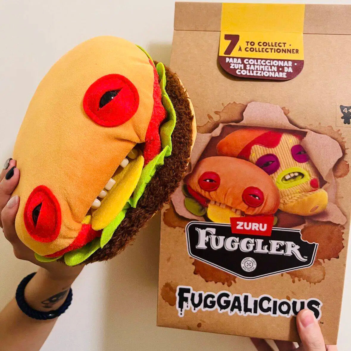 A plush toy resembling a monster face is shown next to its packaging box.