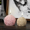 Pink and cream rose flower ball silicone mold with two lit candles against a black and white artistic background