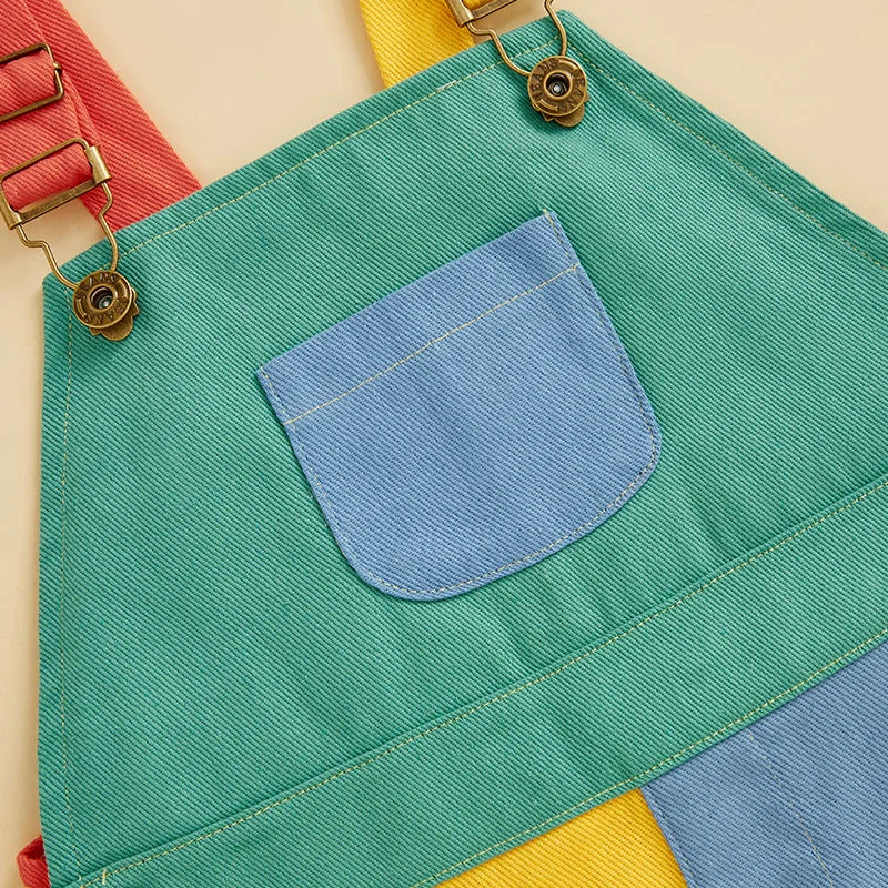 A teal fabric garment with a blue pocket and gold hardware is displayed against a light background.