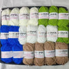 A collection of various colored yarn skeins including white, green, and blue acrylic wool for crafting.