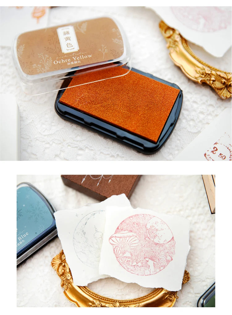 A vintage craft oil-based ink pad in orange-brown color is shown next to white paper and a gold-colored object.