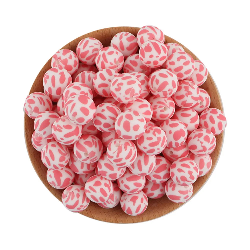A wooden bowl filled with pink and white patterned silicone beads for jewelry making