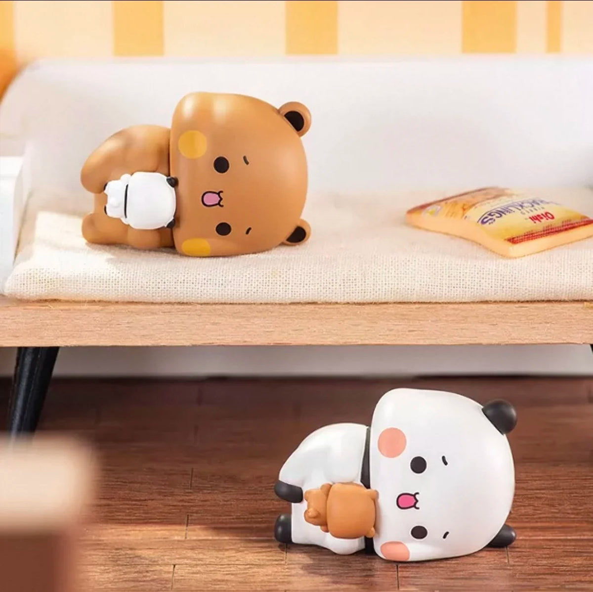 Un par de figuras coleccionables de panda en caja ciega, una marrón y otra blanca, sobre una superficie clara.