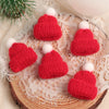 A set of mini knitted red and white hats and scarves for doll dress-up accessories displayed on a lace fabric.